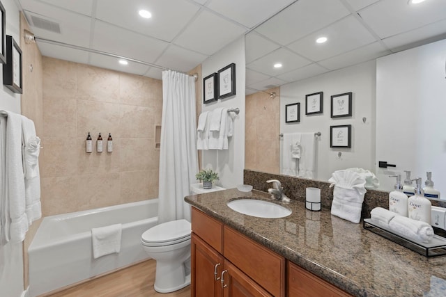 full bathroom with a drop ceiling, wood-type flooring, toilet, shower / tub combo with curtain, and vanity