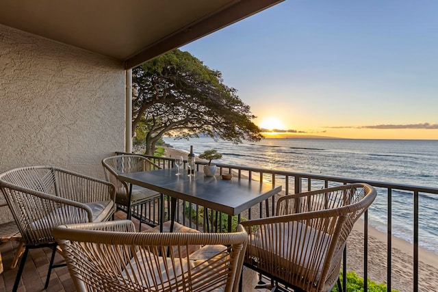 balcony at dusk with a view of the beach and a water view