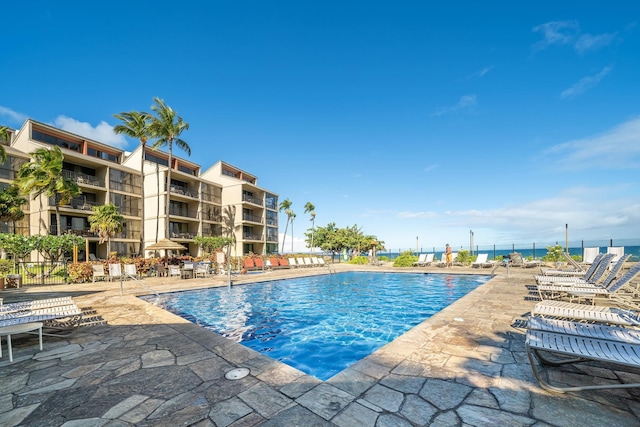 view of swimming pool featuring a water view and a patio