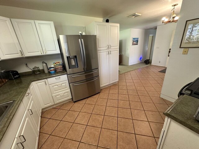 kitchen featuring white cabinetry, stainless steel fridge, light tile patterned flooring, and a chandelier