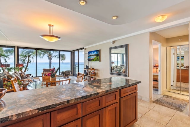 110 Kaanapali Shores Pl Unit 308, Lahaina, HI 96761 - kitchen featuring brown cabinetry, light tile patterned floors, dark stone counters, and healthy amount of natural light