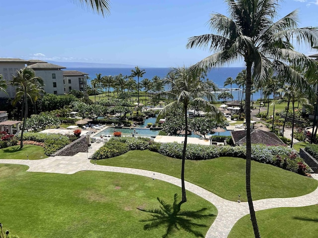 view of home's community with a pool, a lawn, and a water view