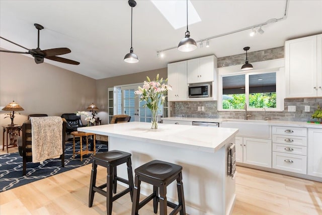 kitchen with white cabinets, light hardwood / wood-style floors, appliances with stainless steel finishes, and rail lighting