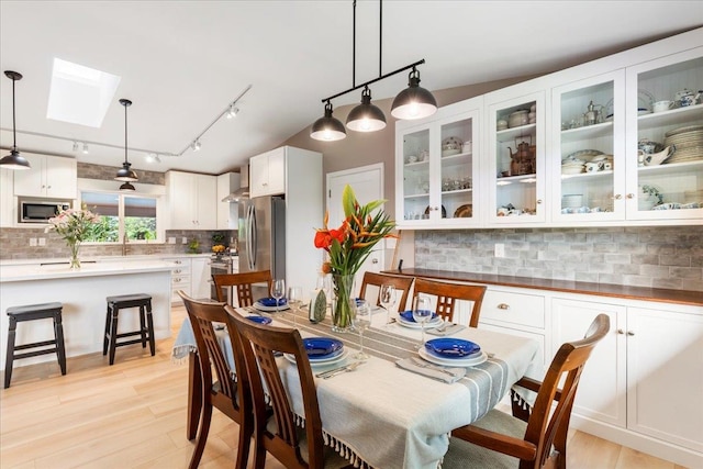 dining area featuring a skylight, light wood-type flooring, and track lighting