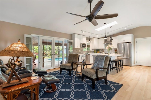 interior space with french doors, light hardwood / wood-style flooring, lofted ceiling with skylight, rail lighting, and ceiling fan