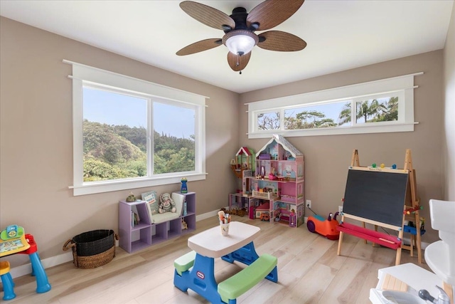 game room with ceiling fan and light wood-type flooring