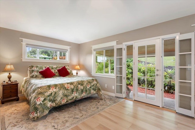 bedroom with french doors, light hardwood / wood-style floors, access to exterior, and multiple windows