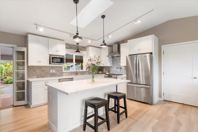 kitchen featuring backsplash, wall chimney exhaust hood, stainless steel appliances, and track lighting