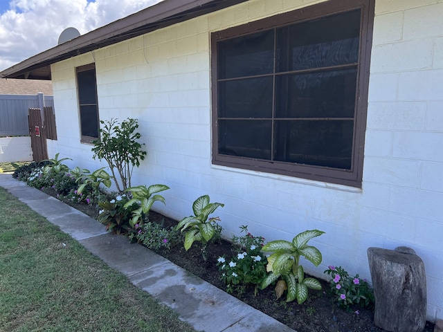 view of side of home featuring concrete block siding and fence