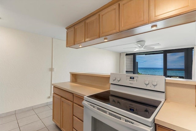 kitchen featuring light tile patterned flooring, white electric range oven, ceiling fan, and a water view