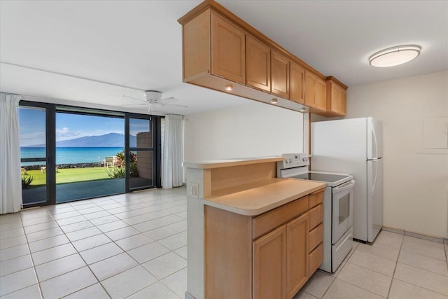 kitchen featuring ceiling fan, white appliances, light tile patterned floors, and a water view