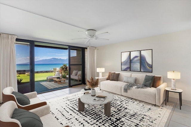 living room with light tile patterned flooring, a water view, and ceiling fan