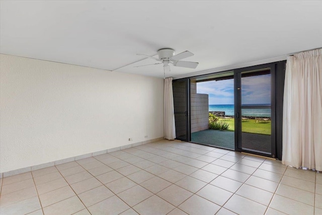 empty room with a water view, expansive windows, light tile patterned flooring, and ceiling fan