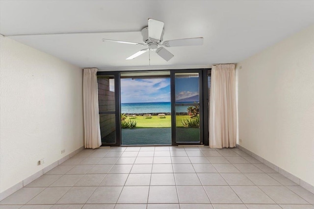 empty room featuring a wall of windows, light tile patterned floors, and ceiling fan