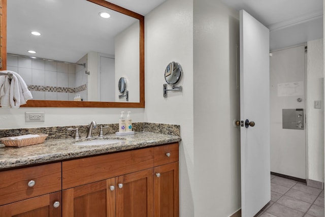 bathroom featuring vanity, tile patterned flooring, recessed lighting, baseboards, and a tile shower