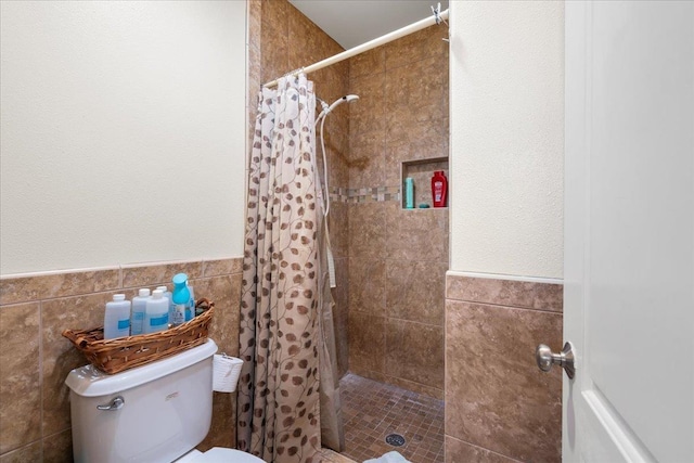 full bath featuring toilet, a stall shower, tile walls, and a wainscoted wall