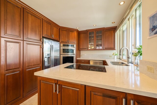 kitchen featuring light stone counters, appliances with stainless steel finishes, sink, and kitchen peninsula