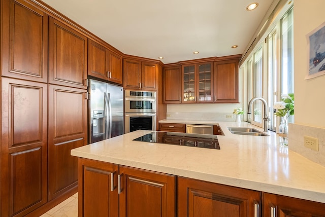 kitchen with appliances with stainless steel finishes, sink, light tile patterned floors, kitchen peninsula, and light stone countertops