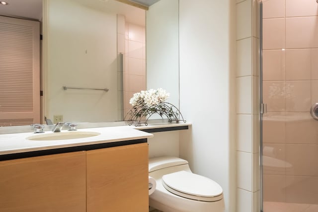 bathroom with vanity, a shower with door, and toilet