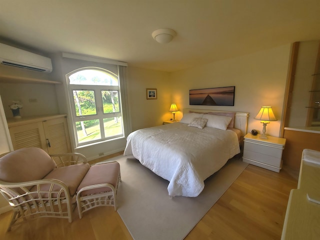 bedroom with a wall unit AC and light wood-type flooring