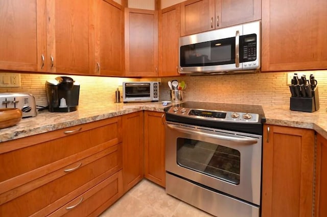 kitchen with decorative backsplash, light tile patterned floors, stainless steel appliances, and light stone counters