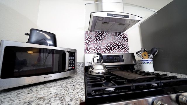 kitchen with decorative backsplash, stainless steel appliances, light stone countertops, and exhaust hood