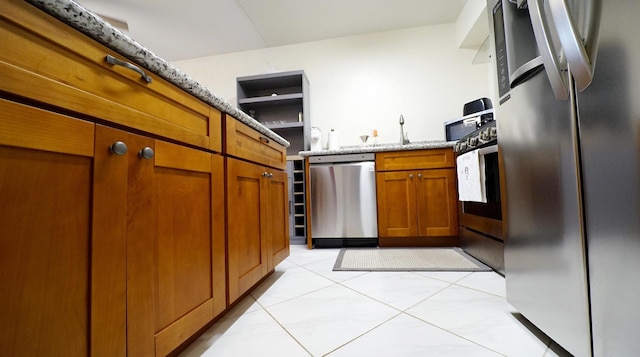 kitchen featuring light tile patterned floors, light stone countertops, and appliances with stainless steel finishes