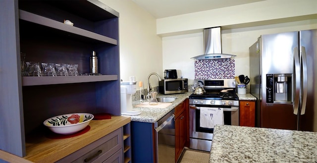 kitchen featuring appliances with stainless steel finishes, sink, light stone counters, and wall chimney range hood