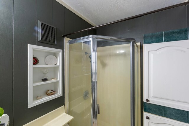 bathroom with a shower stall, visible vents, and built in features