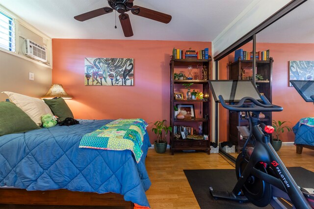 bedroom with wood finished floors, a ceiling fan, and an AC wall unit