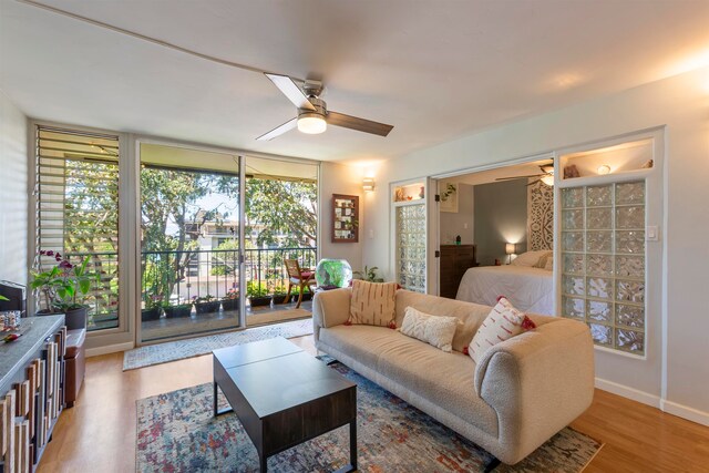 living area featuring baseboards, ceiling fan, and wood finished floors