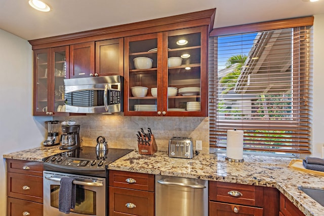 kitchen with stainless steel appliances, light stone countertops, and decorative backsplash