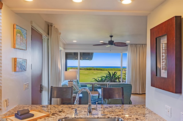 kitchen with a sink, light stone counters, recessed lighting, and a ceiling fan