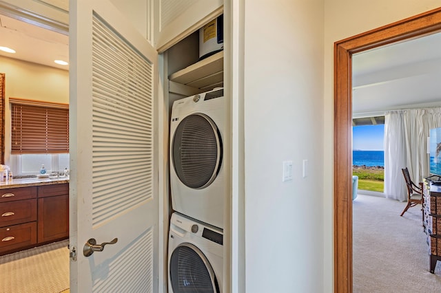 laundry room with stacked washer / drying machine, light carpet, and laundry area