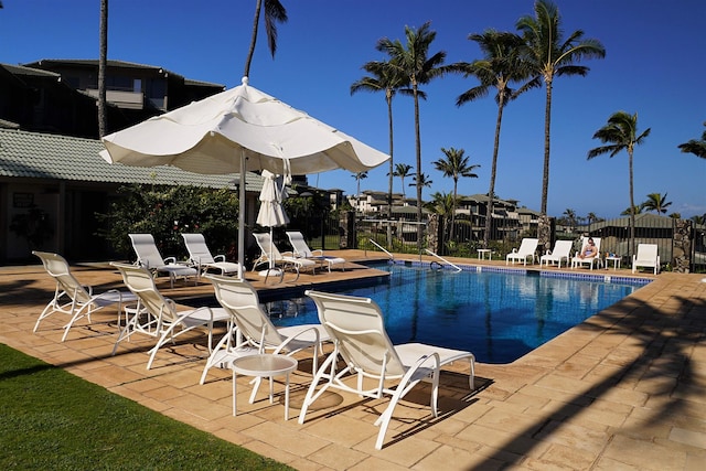 community pool with a patio area and fence