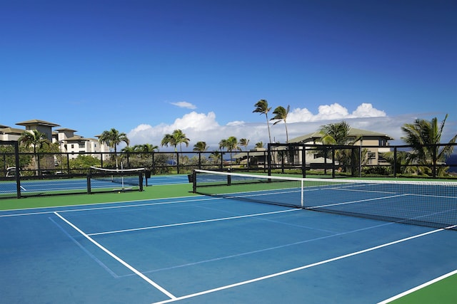 view of tennis court with community basketball court and fence