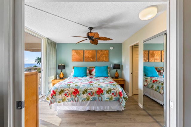 bedroom with a textured ceiling, ceiling fan, and light hardwood / wood-style flooring