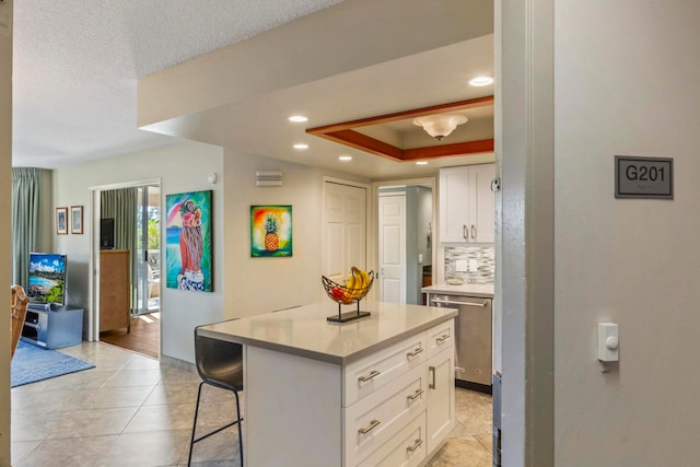 kitchen featuring a breakfast bar, dishwasher, a center island, white cabinets, and decorative backsplash