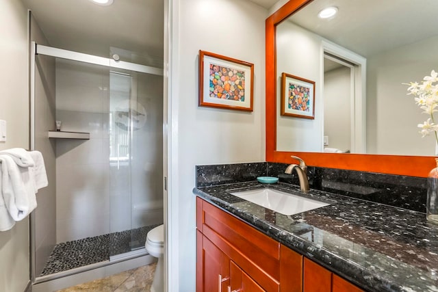 bathroom featuring tile patterned floors, vanity, toilet, and a shower with door