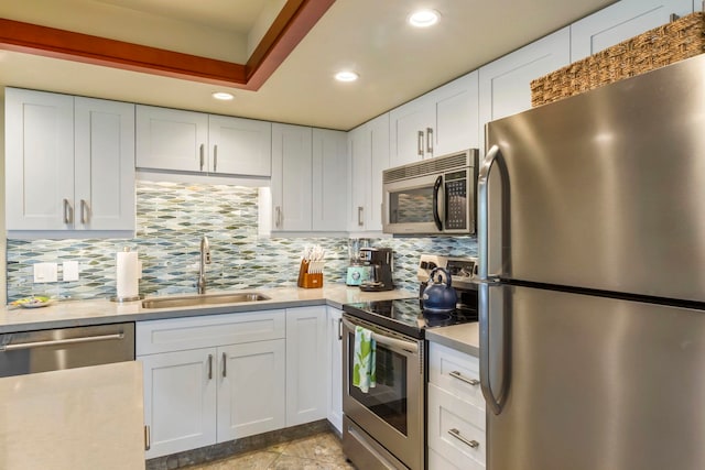 kitchen featuring sink, white cabinetry, light tile patterned floors, appliances with stainless steel finishes, and decorative backsplash