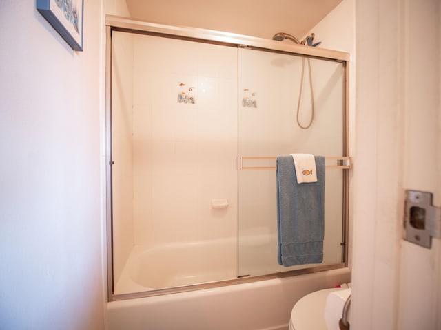 bathroom featuring toilet and bath / shower combo with glass door