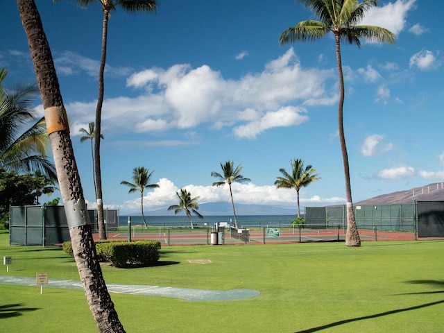 view of property's community with tennis court and a lawn