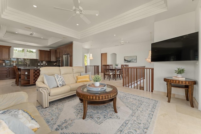 living room with a raised ceiling and crown molding