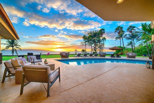 pool at dusk featuring an outdoor living space, a water view, and a patio