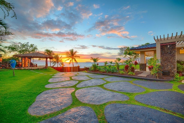 yard at dusk featuring a water view, a patio area, and a gazebo