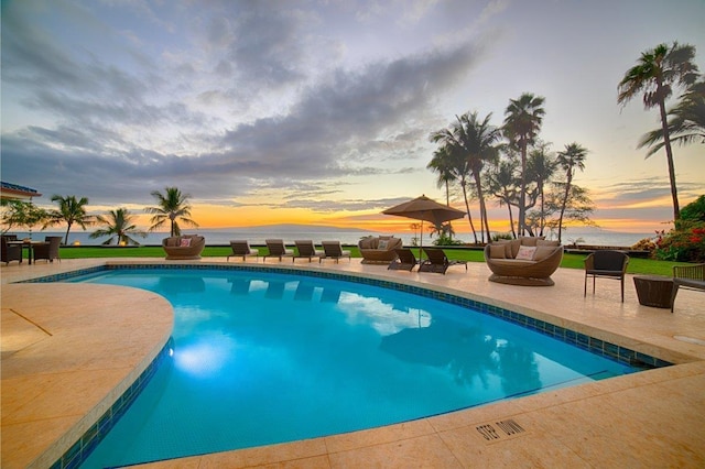 pool at dusk with an outdoor living space and a patio