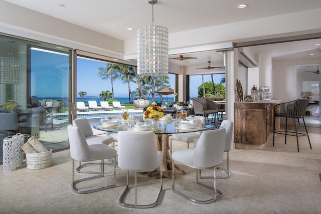 dining room featuring a water view and ceiling fan with notable chandelier