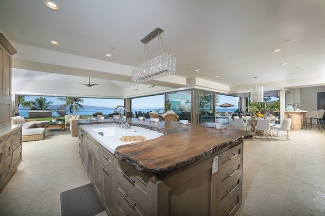 kitchen with ceiling fan, a large island with sink, hanging light fixtures, and sink