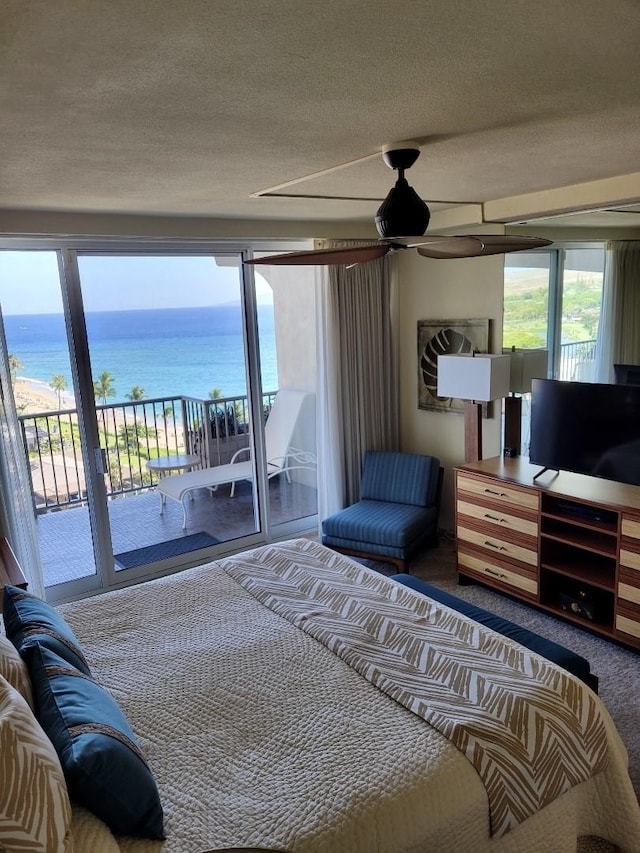 carpeted bedroom with a water view, ceiling fan, access to outside, and a textured ceiling