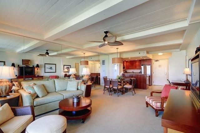 living room with ceiling fan, beamed ceiling, and light colored carpet